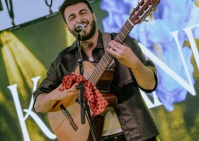 Blas Menchén cantando con guitarra flamenca delante del logo KALANDA