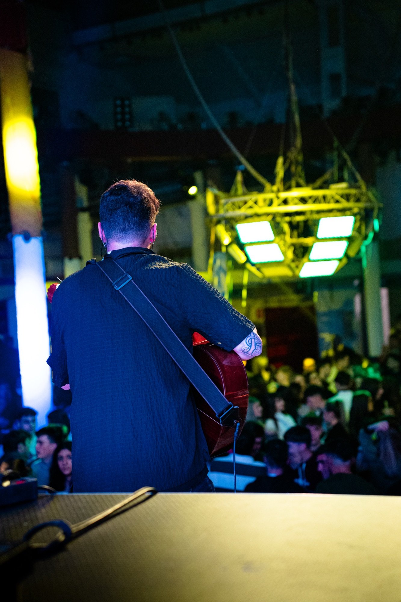 Blas Menchén de espaldas tocando la guitarra frente al público