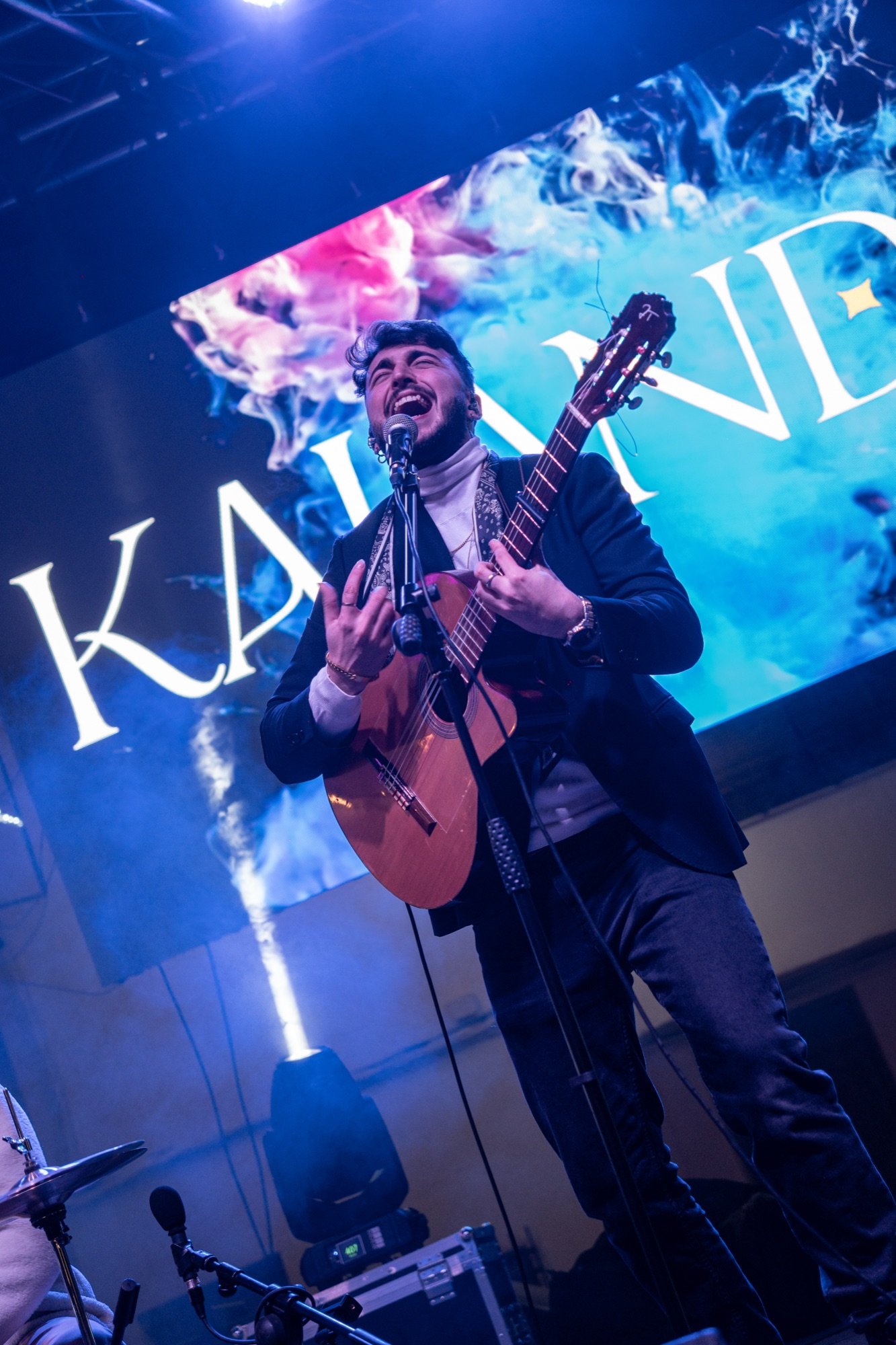 Blas Menchén cantando con pasión con la guitarra flamenca delante del logo KALANDA
