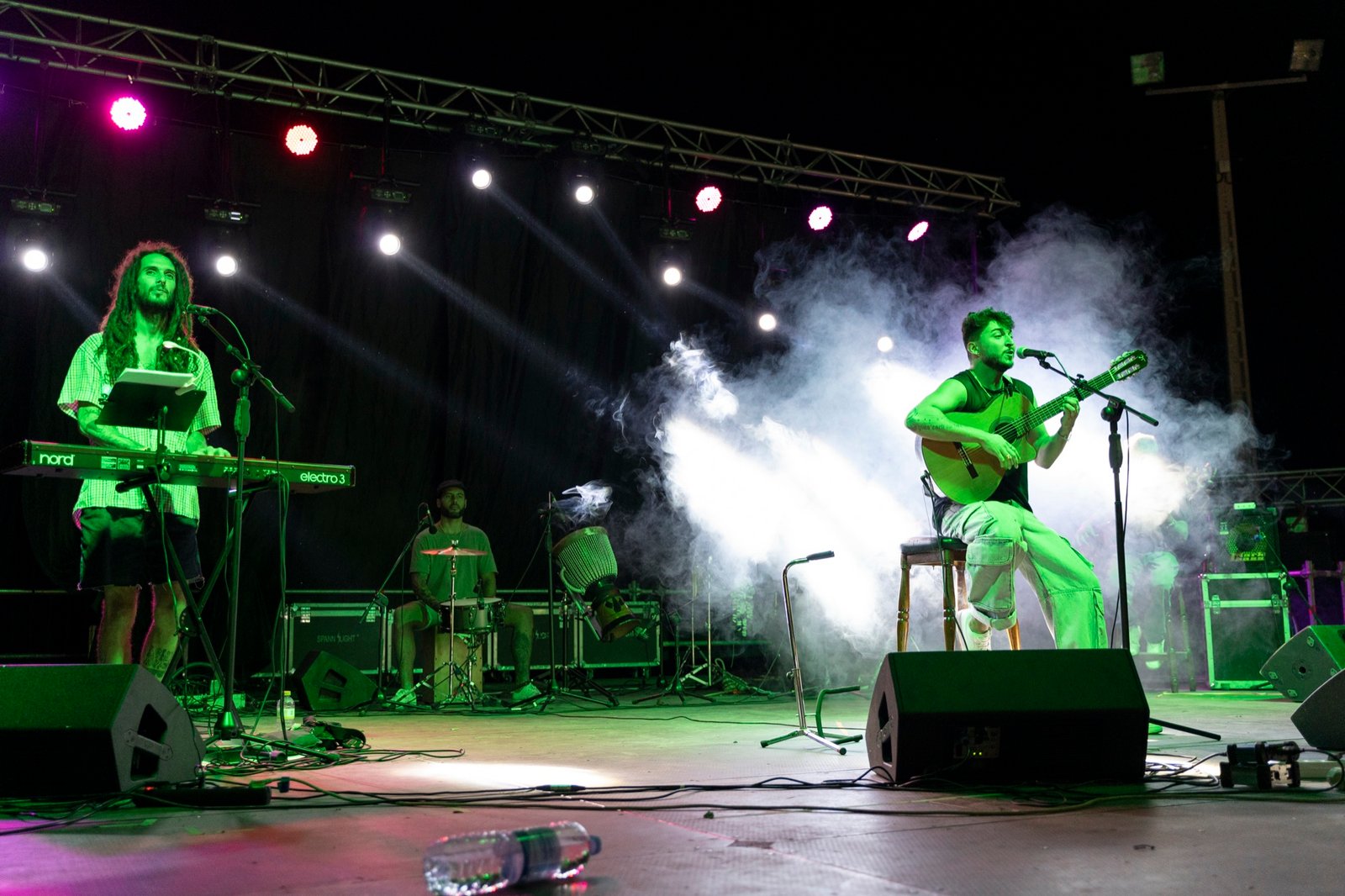 Grupo Kalanda tocando en un escenario al aire libre entre humo y luces