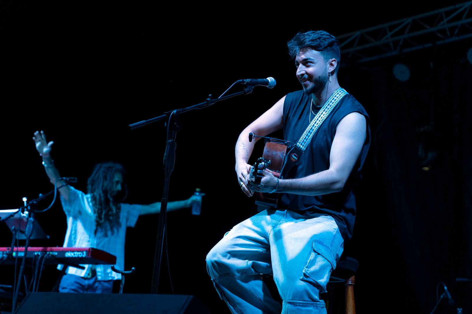 Blas Menchén cantando sentado con la guitarra en un concierto