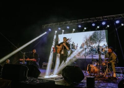 Blas Menchén con la guitarra en un concierto de Grupo Kalanda con focos blancos