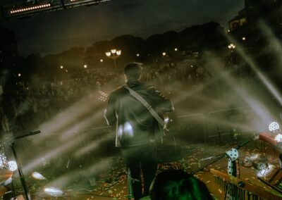 Blas Menchén de espaldas tocando la guitarra frente al público entre humo y luces