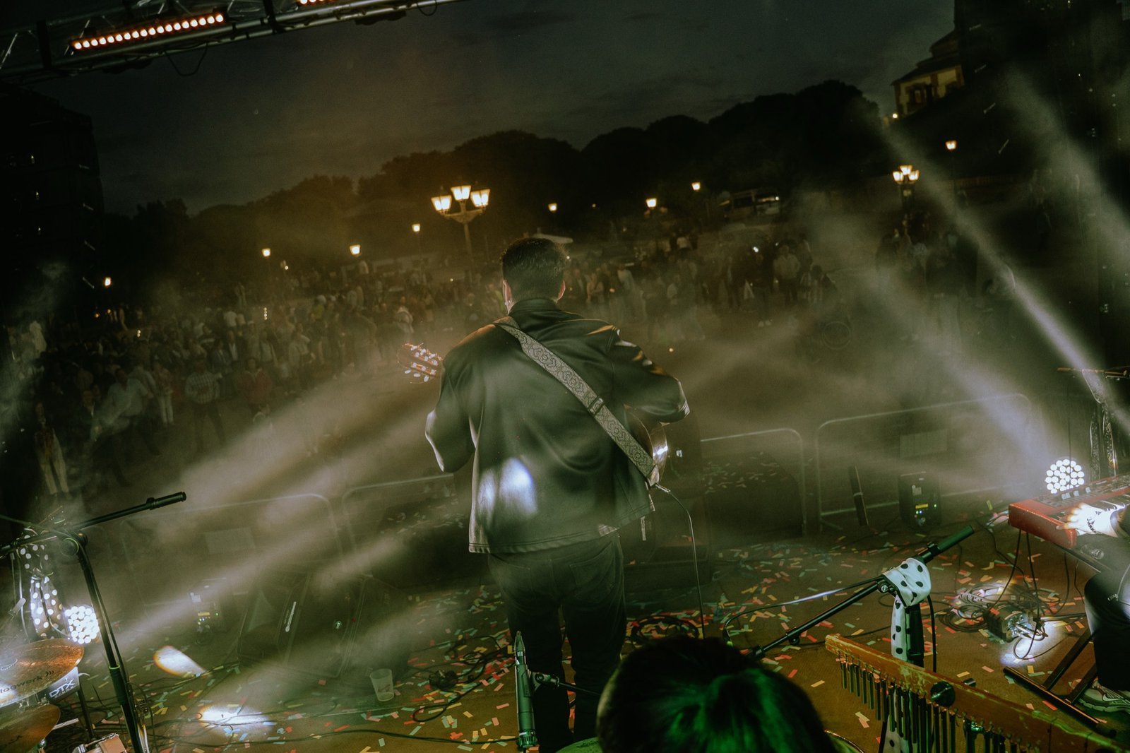 Blas Menchén de espaldas tocando la guitarra frente al público entre humo y luces
