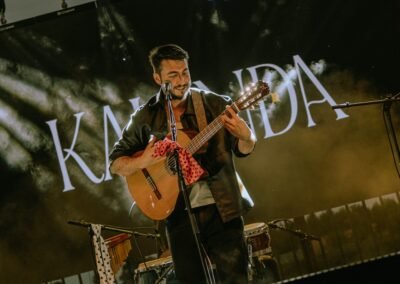 Blas Menchén tocando la guitarra flamenca con el logo KALANDA de fondo