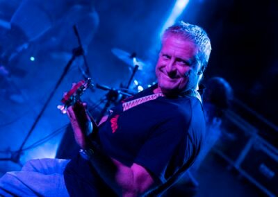 Bajista de Grupo Kalanda sonriendo en un concierto con luz azul