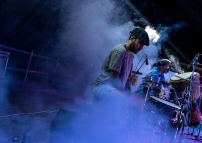 Músico de Grupo Kalanda tocando entre humo y luces en el escenario