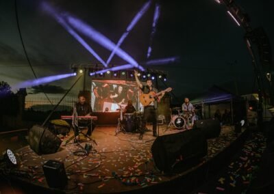 Concierto de Grupo Kalanda al anochecer con luces y confeti en el escenario